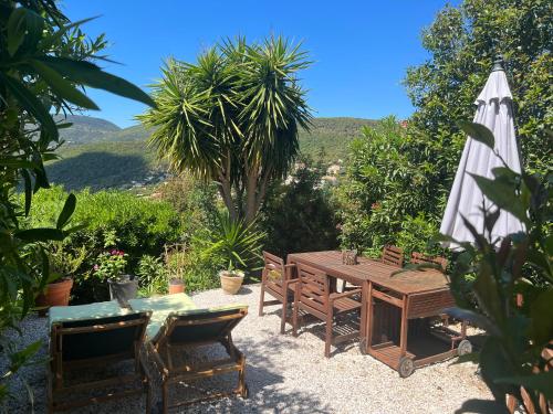 un patio avec une table, un parasol et des chaises dans l'établissement LA MAISON D'AUREL, à La Croix-Valmer