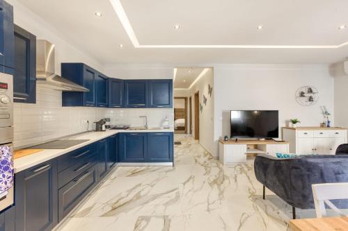 a large kitchen with blue cabinets and a tv at Bluebell Apartment in Sliema in Sliema