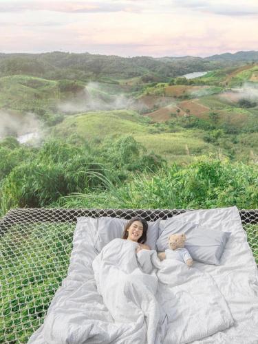 a woman laying on a bed with a teddy bear at Papa Garden Khaokho in Khao Kho