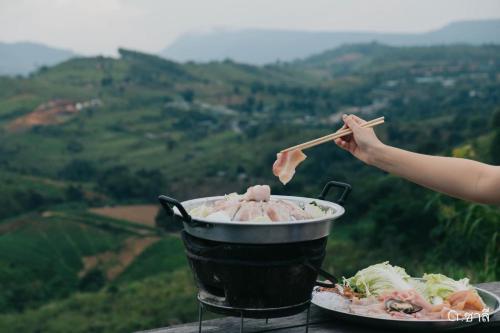 a person is cooking food on a grill with chopsticks at Papa Garden Khaokho in Khao Kho