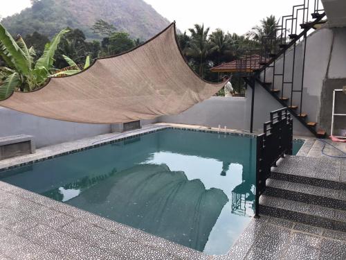 a swimming pool with a hammock on the side of a house at Vila Gunung Batu inces in Bogor