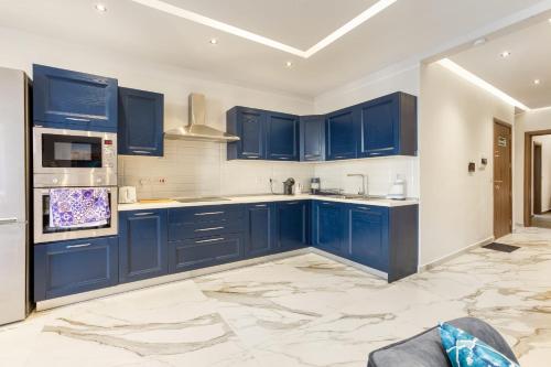 una cocina azul con paredes blancas y armarios azules en Bluebell Apartment-Hosted by Sweetstay en Sliema