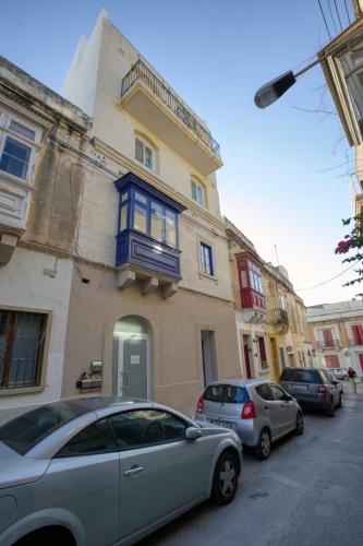 two cars parked in front of a building with a blue window at Bluebell Apartment in Sliema in Sliema