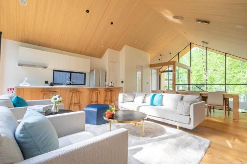 a living room with white couches and a kitchen at Kouzan Woods in Kaributo