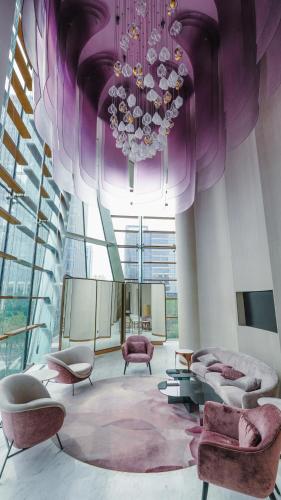 a large room with a chandelier and pink furniture at MGM Qingdao in Qingdao