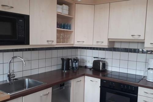 een keuken met witte kasten en een wastafel bij Nordhörnchen! Sehr zentral, trotzdem ruhig! in Nordhorn