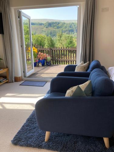 a living room with two blue couches and a sliding glass door at The Dale at Greystones - Luxurious annexe with stunning view in Buckden