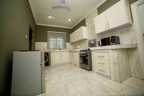a large kitchen with white cabinets and a refrigerator at 3 bedrooms, Entire Flat, Amasaman - Accra in Amasaman