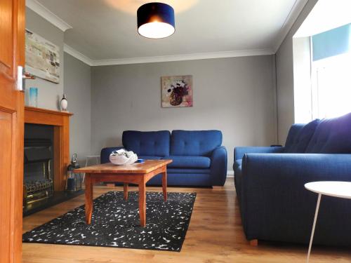 a living room with a blue couch and a table at Butland House in Pembrokeshire