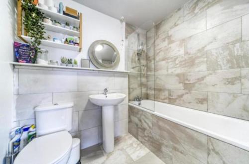 a bathroom with a toilet and a sink and a bath tub at Light & Airy Oasis in South Norwood