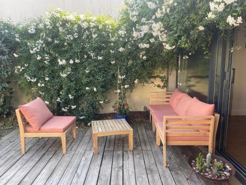 2 chaises et une table sur une terrasse fleurie dans l'établissement Duplex confort et jardin charmant, à Nantes