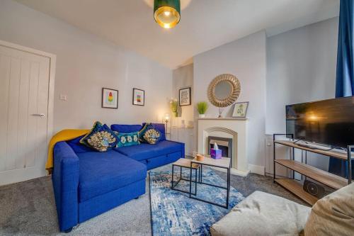 a living room with a blue couch and a tv at Castleford Stay, Families & Work Trips at Liquorice Lodge in Castleford