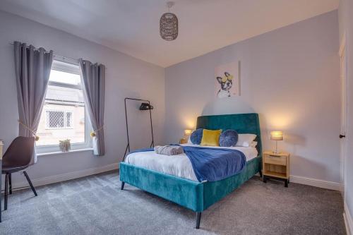 a bedroom with a bed with a blue headboard at Liquorice Lodge- 2 bed & parking in Castleford