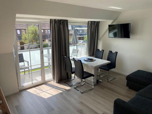 a living room with a table and chairs and a balcony at Seaside-Amrum-15 in Norddorf