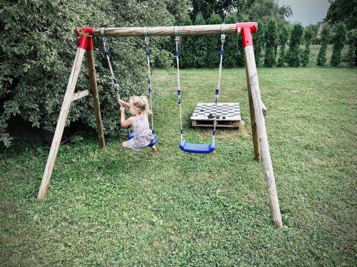 a little girl playing on a swing in a yard at Plateliai Samogitia Barn in Plateliai