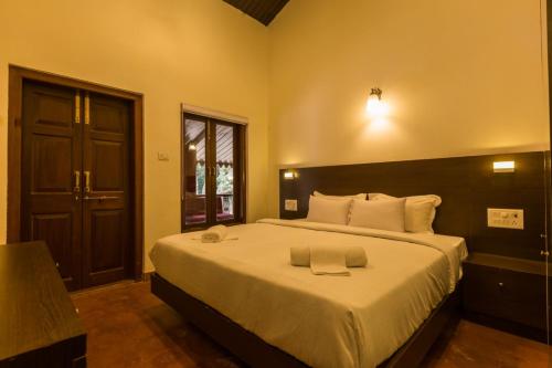 a bedroom with a large bed with white sheets at Greenfield Resort, Matheran in Matheran