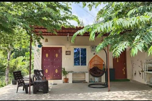 a house with a patio with a table and chairs at Sattva Farmstay in Bangalore