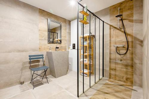 uma casa de banho com um chuveiro, um banco e um lavatório. em Maryse em Douvrin