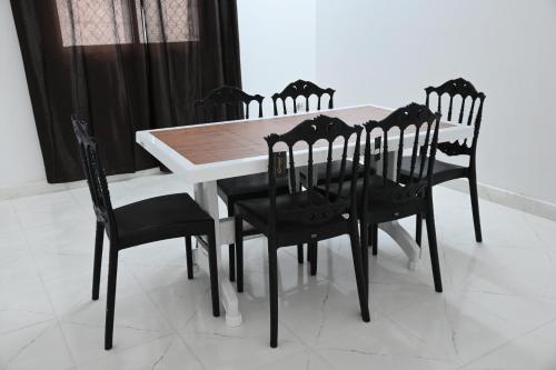 d'une table à manger entourée de chaises noires. dans l'établissement New Furnished Apartment, à Djibouti