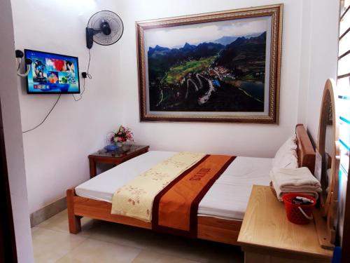 a bedroom with a bed and a painting on the wall at Yen Minh Thien An Motel in Yên Minh