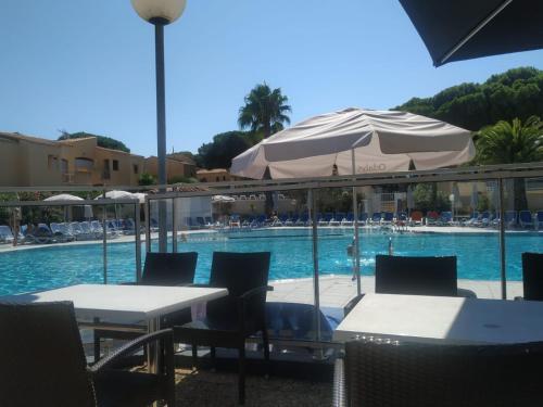 a pool with tables and umbrellas and a swimming pool at Studio Climatisé Résidence Odalys Saint Loup,piscine ,parking privé et superette in Cap d'Agde