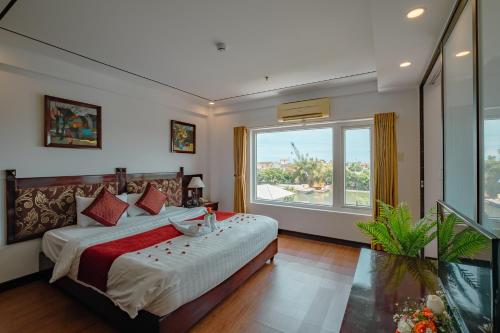 a bedroom with a bed and a large window at Vina Hotel Hue in Hue