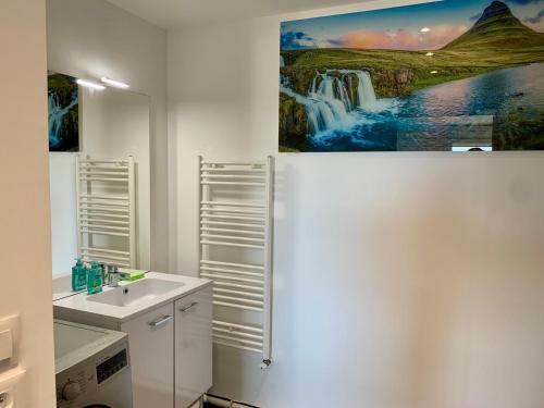 La salle de bains est pourvue d'un lavabo et d'une peinture murale représentant une cascade. dans l'établissement Superbe appartement vue mer, à Trouville-sur-Mer