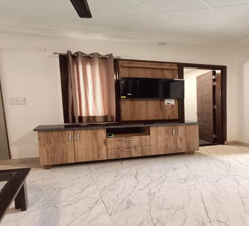 a living room with a large wooden cabinet with a microwave at 85 The Ganges 2 BHK Apartment for Homestay in Rishīkesh