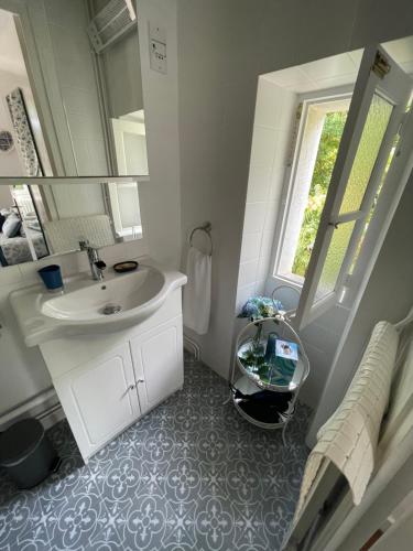 a white bathroom with a sink and a mirror at Vue du Château d'Excideuil en chambres in Excideuil