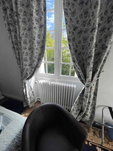 a chair sitting in front of a window with curtains at Vue du Château d'Excideuil en chambres in Excideuil