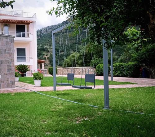 dos sillas en un columpio en el patio de una casa en Belvedere Hotel & Suites, en Himare