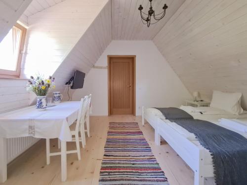 a attic room with two beds and a dining table at Haus Rether - Transylvanian Guesthouse in Buneşti