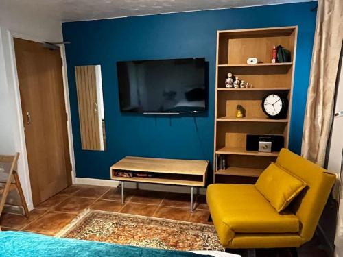 a living room with a tv and a yellow chair at Exclusive flat in Oxford Centre with AC in Oxford