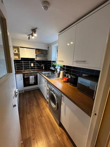 a kitchen with white cabinets and a washer and dryer at Exclusive flat in Oxford Centre with AC in Oxford