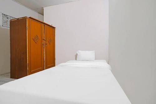 a bedroom with a bed and a wooden cabinet at OYO Life 92694 Kost Nino in Bandung