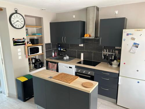 - une cuisine avec des armoires noires et un réfrigérateur blanc dans l'établissement La Maison d'Augustin en Périgord, à Limeyrat