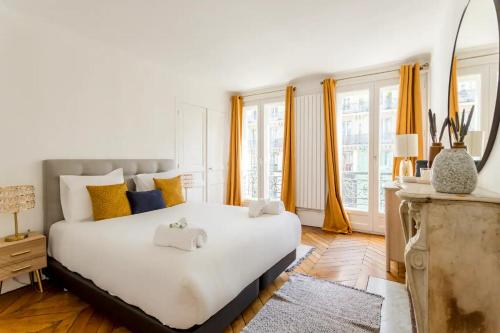 - une chambre avec un grand lit blanc et des rideaux jaunes dans l'établissement 8P - 3BR Le Marais Spacious - Central - Historic Apt, à Paris