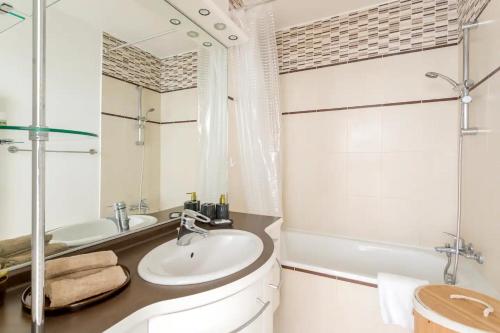 een badkamer met een wastafel, een bad en een spiegel bij Spacious, Central & Historic Getaway - 5 Star Location in Parijs