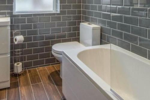 Sleep up to 14 - Doncaster central في دونكاستير: حمام به مرحاض أبيض وحوض استحمام