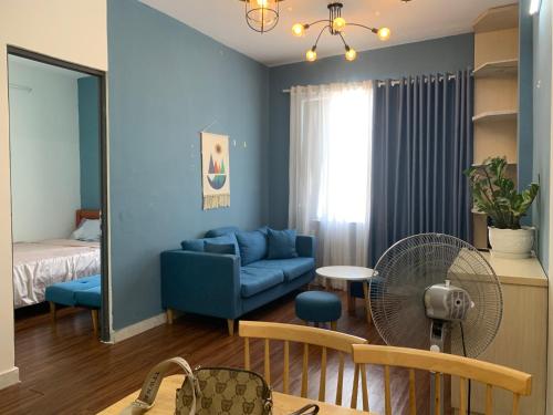 ein Wohnzimmer mit einem blauen Sofa und einem Ventilator in der Unterkunft HOMESTAY KHÁCH SẠN NINH THUẬN in Thôn Mỹ Phước