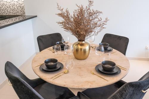 a wooden table with wine glasses and a vase at Stylish 2Bedroom w infinity pool on the 64th floor in Dubai