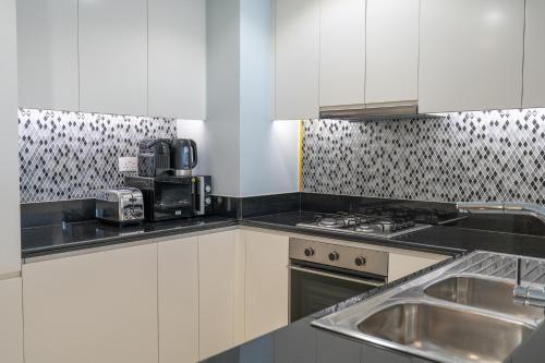 a kitchen with white cabinets and a sink at Stylish 2Bedroom w infinity pool on the 64th floor in Dubai