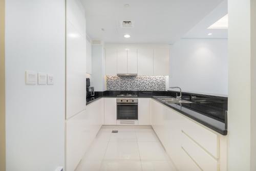 a white kitchen with a sink and a stove at Stylish 2Bedroom w infinity pool on the 64th floor in Dubai