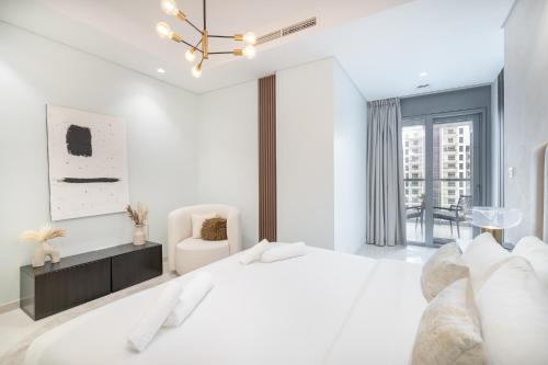 a white bedroom with a bed and a chair at Stylish 2Bedroom w infinity pool on the 64th floor in Dubai
