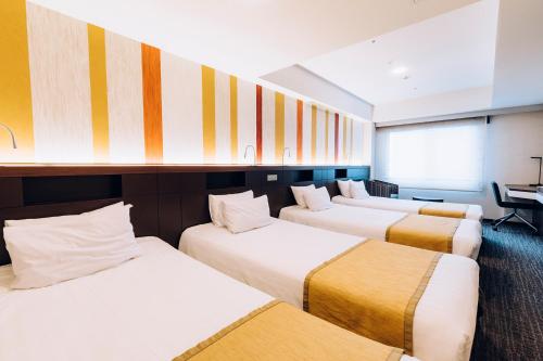rząd trzech łóżek w pokoju w obiekcie Shinagawa Tobu Hotel w Tokio