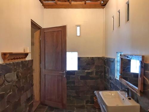 ein Badezimmer mit einer Holztür und einem Waschbecken in der Unterkunft Rambai Tree Jungle Lodges in Bukit Lawang