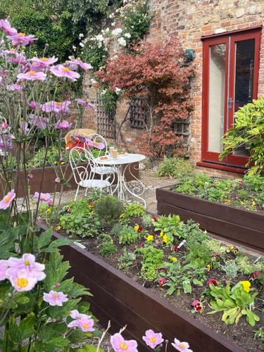 a table and chairs in a garden with flowers at Centre of town House 3 Bedrooms Sleeps 5 and Infant Free Onsite Parking 2 Cars in King's Lynn