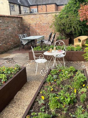 a patio with a table and chairs in a garden at Centre of town House 3 Bedrooms Sleeps 5 and Infant Free Onsite Parking 2 Cars in King's Lynn