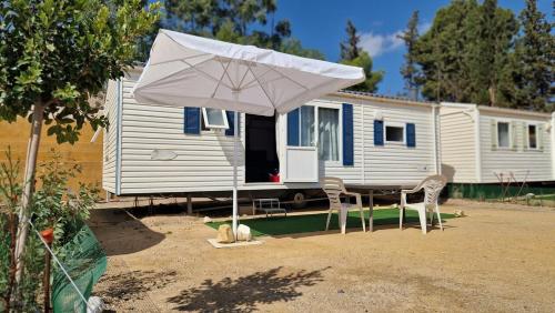 a white umbrella and chairs in front of a caravan at Camping Albox in Albox