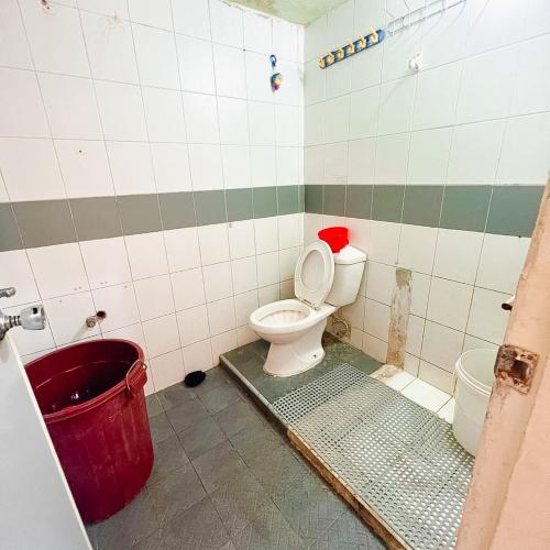 a bathroom with a toilet and a red bucket at VILLA BUKIT MAS BERASTAGI DEPAN MIKIE FUNLAND in Berastagi